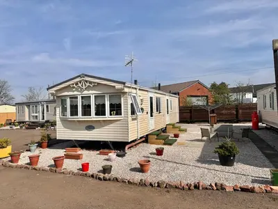 a tiny house in a yard with potted plants at Willerby Granada 2-Bedroom Located in Uddingston, Glasgow at Maryville Caravan Site in Uddingston
