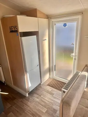 an empty room with a refrigerator and a window at Two Bedroom Willerby Caravan Located in Uddingston, Glasgow at Maryville Caravan Site in Uddingston