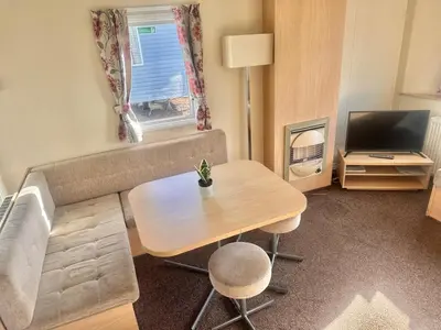 a small living room with a table and a television at Two Bedroom Willerby Caravan Located in Uddingston, Glasgow at Maryville Caravan Site in Uddingston