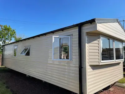 a small white trailer with windows on a street at Two Bedroom Willerby Caravan Located in Uddingston, Glasgow at Maryville Caravan Site in Uddingston