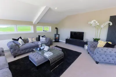 a living room with couches and a tv at Arran View Apartment at Heads of Ayr in Ayr