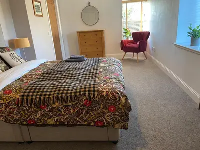 a bedroom with a bed and a red chair at The Granary in Stirling