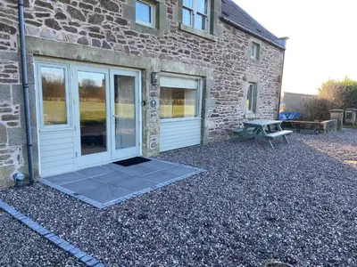a stone house with a door and a picnic table at The Granary in Stirling