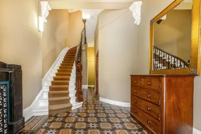 a hallway with a staircase with a mirror and a dresser at Beautiful Double Room in Idyllic West End Townhouse in Glasgow
