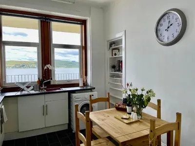 a kitchen with a table and a clock on the wall at A Shore Stay in Gourock