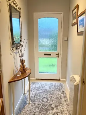 a hallway with a door and a table and a mirror at Cedar Lodge in Oban