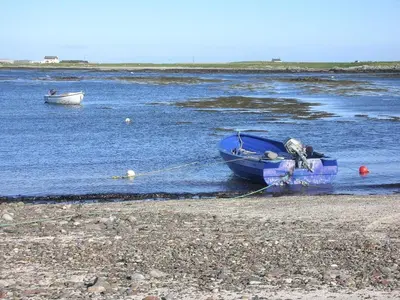 a blue boat sitting on the shore of a body of water at Cedar Lodge in Oban