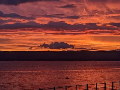 a sunset over a body of water with a fence at Strathclyde Cottage North in Skelmorlie