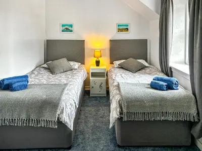 a bedroom with two beds and a lamp on a table at Fiddlers Rest in Ballantrae