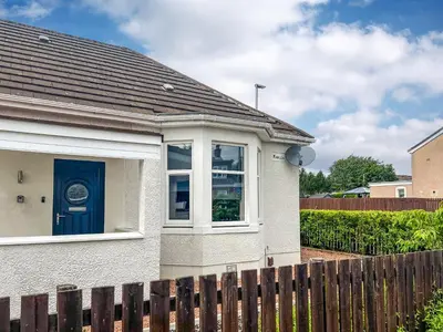 a white house with a blue door and a fence at Kirklea in Wishaw