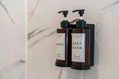 two bottles of body wash sitting on a wall at One Bed Holiday Home in the Heart of Glasgow in Glasgow
