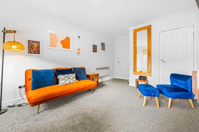 a living room with an orange couch and two blue chairs at One Bed Holiday Home in the Heart of Glasgow in Glasgow