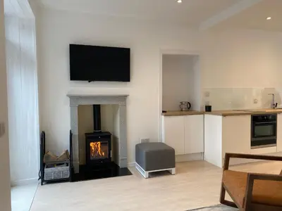 a living room with a fireplace with a television and a stove at Hugmish in Tighnabruaich