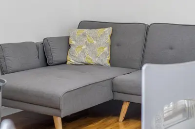 a gray couch with a yellow pillow on it at 1 bed apartment central Hamilton free wifi with great transport links to Glasgow in Hamilton