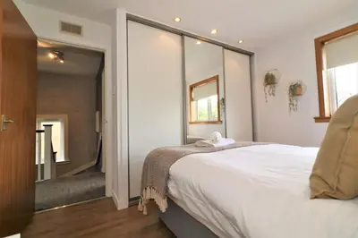 a bedroom with a large white bed and a mirror at Signature - Binnie House in Cumbernauld