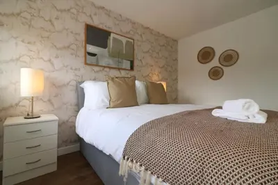 a bedroom with a bed and a lamp on a night stand at Signature - Binnie House in Cumbernauld