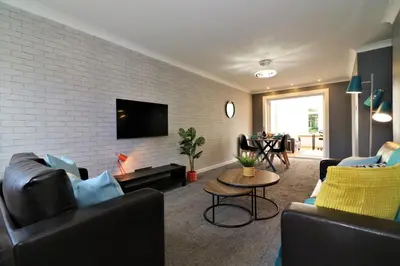 a living room with couches and a brick wall at Signature - Binnie House in Cumbernauld