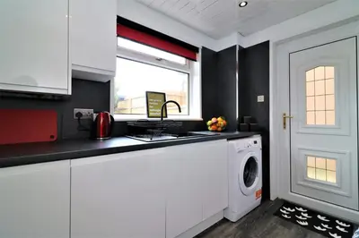 a kitchen with white cabinets and a washing machine at Signature - Binnie House in Cumbernauld