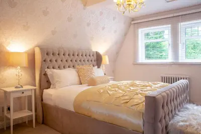 a bedroom with a large bed and a chandelier at Stunning 4-Bedroom Country House with Hot Tub & Sauna near Loch Lomond in Glasgow