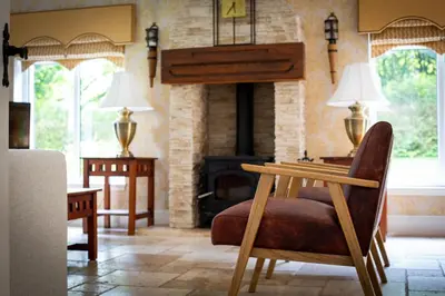 a living room with a chair and a fireplace at Stunning 4-Bedroom Country House with Hot Tub & Sauna near Loch Lomond in Glasgow