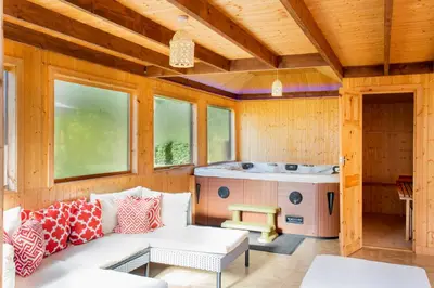 a living room with a couch and a hot tub at Stunning 4-Bedroom Country House with Hot Tub & Sauna near Loch Lomond in Glasgow