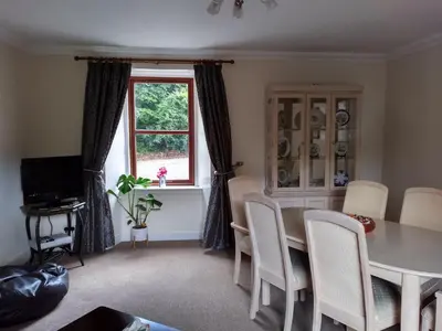 a dining room with a table and chairs and a window at Beautiful Farm House at the foot of Ben More. in Crianlarich