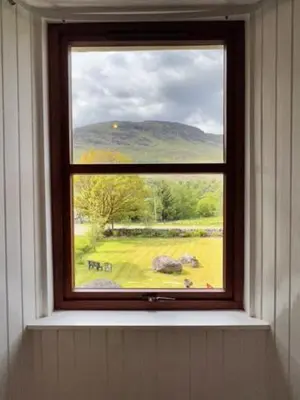a window in a room with a view of a field at Beautiful Farm House at the foot of Ben More. in Crianlarich