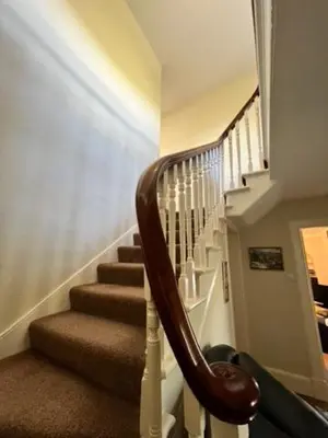 a staircase in a home with a wooden stair case at Beautiful Farm House at the foot of Ben More. in Crianlarich