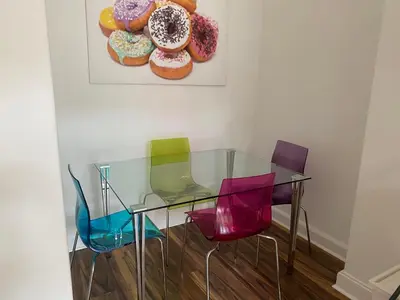 a glass table with four colorful chairs and a painting of donuts at Lovely main door 2 bed apartment in Edinburgh