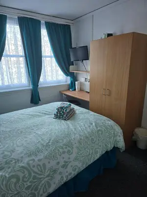 a bedroom with a bed and a dresser and windows at The Waterfront in Greenock