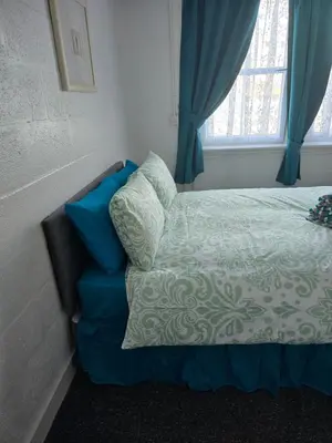 a bedroom with a bed with blue curtains and a window at The Waterfront in Greenock