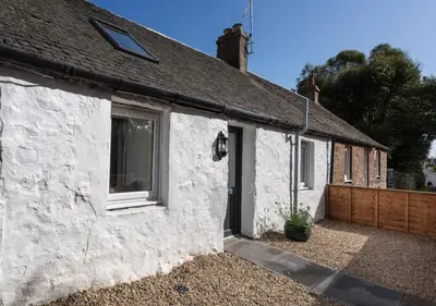 a white cottage with a window and a fence at Ideal Couples base for exploring the Isle of Arran in Shiskine