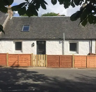 a white house with a wooden fence in front of it at Ideal Couples base for exploring the Isle of Arran in Shiskine