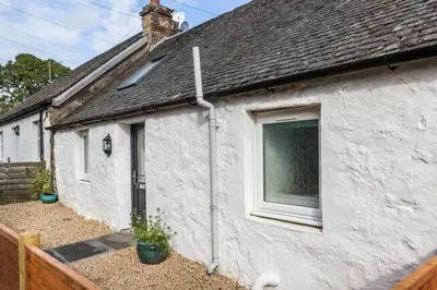 a white house with a window on the side of it at Ideal Couples base for exploring the Isle of Arran in Shiskine