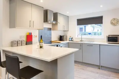 a kitchen with white cabinets and a counter top at Ideal Couples base for exploring the Isle of Arran in Shiskine