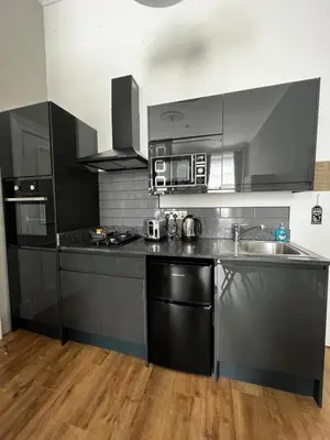 a kitchen with stainless steel appliances and wooden floors at Amani Apartments - Glasgow City Centre in Glasgow