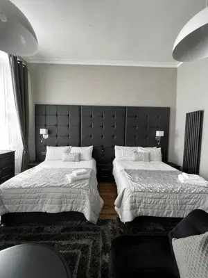 a bedroom with two beds and a large headboard at Amani Apartments - Glasgow City Centre in Glasgow