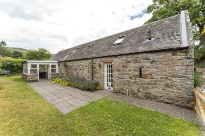 an exterior view of a stone cottage with a patio at Garden Cottage in Gargunnock