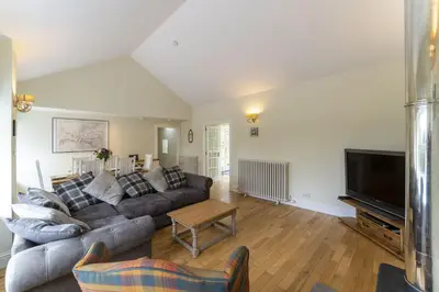 a living room with a couch and a tv at Garden Cottage in Gargunnock