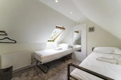 a attic bedroom with two beds and a mirror at Garden Cottage in Gargunnock