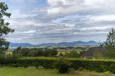 a view from the garden of a house with mountains in the background at Garden Cottage in Gargunnock