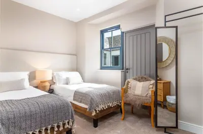 a bedroom with two beds and a mirror and a chair at Rachel's Farm luxury escapes with Hots Tubs in Buchlyvie