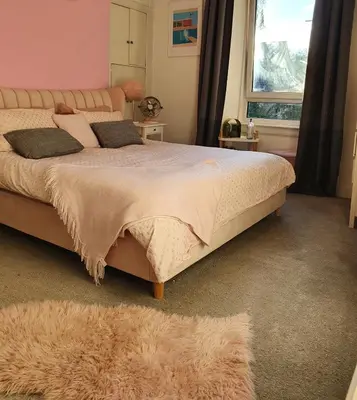 a bedroom with a large bed and a window at The Flat with the Pink Door in Edinburgh