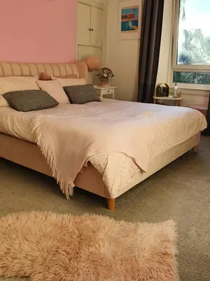 a bedroom with a large bed with a furry rug at The Flat with the Pink Door in Edinburgh