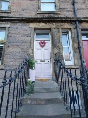 a white door with a heart wreath on it at The Flat with the Pink Door in Edinburgh