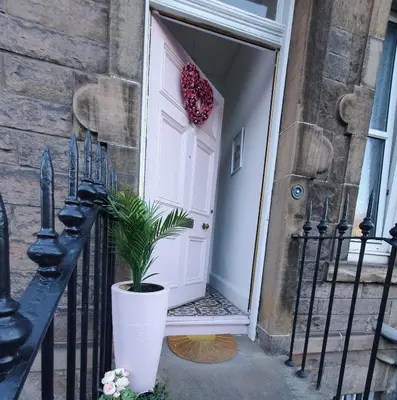 a white door with a potted plant in front of it at The Flat with the Pink Door in Edinburgh