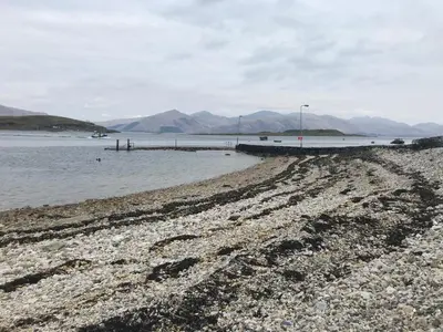 a rocky beach with a pier in the water at Riverside Loft in Barcaldine