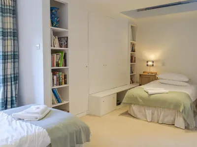 a bedroom with two beds and a book shelf at Tigh Nam Muc in Loanhead