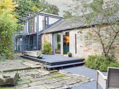 a stone house with a porch and a glass extension at Tigh Nam Muc in Loanhead