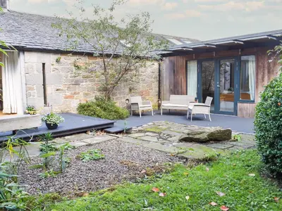 a patio with two chairs and a table next to a building at Tigh Nam Muc in Loanhead